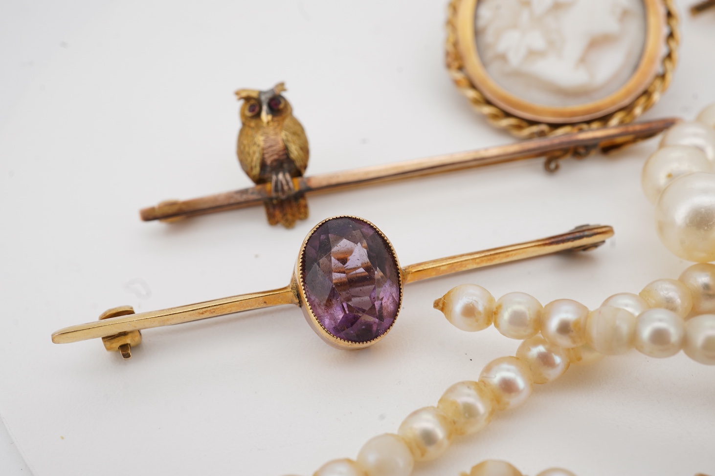 A 9ct owl bar brooch, with cabochon eyes, 50mm, a 1960's 9ct gold and amethyst set bar brooch, an 18ct and amethyst set bar brooch, a cameo brooch(a.f.) and a cultured pearl necklace with 9ct gold clasp.